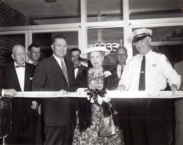 A ribbon-cutting ceremony at the dedication of the new Skokie police headquarters at 8333 Lincoln Avenue:  left to right:  Jack Seeley, Ray Krier, Ambrose Reiter, Jum Smith, Mrs. Wilson, Bill Krewer, Police Chief William Griffin
